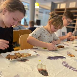Uczniowie podczas warsztatów dekorują lukrem pierniczki.