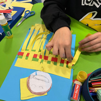 Dziecko tworzy kolorową kołderkę - przeplatankę z papierowych pasków.