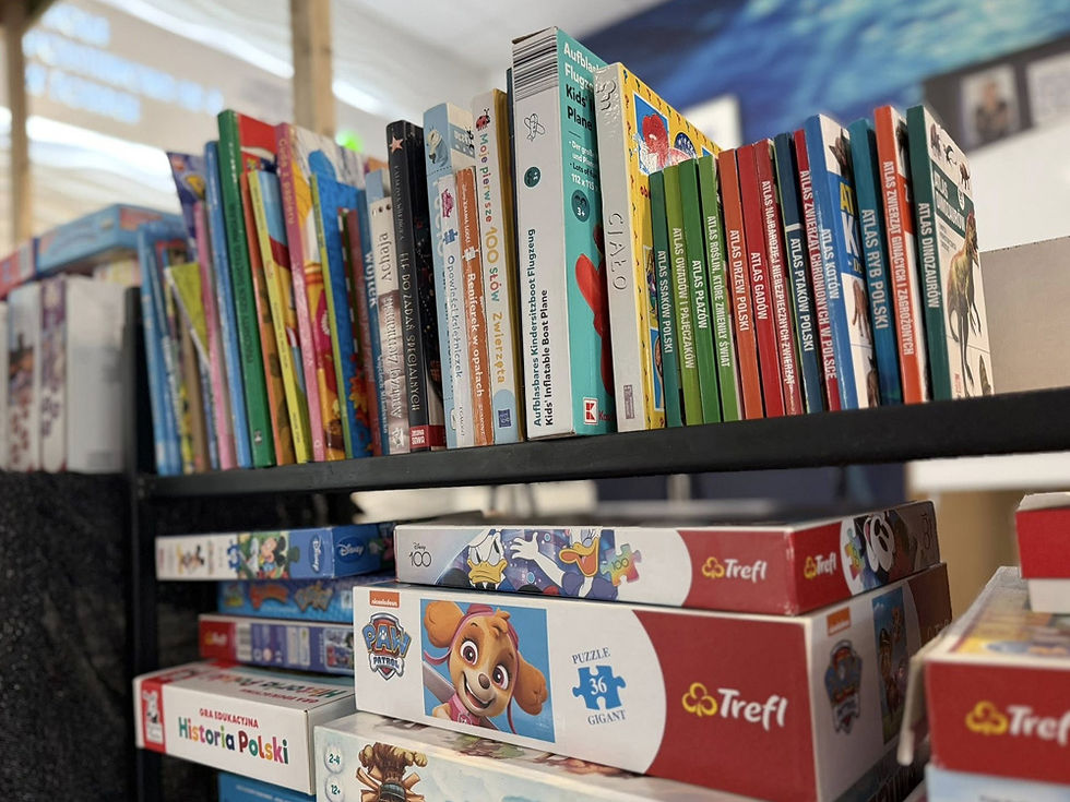 Półki zastawione książkami, grami i układankami.