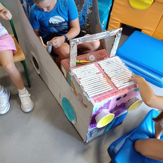 Dzieci w świetlicy wspólnie budują i ozdabiają samochód z kartonu.