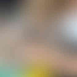 Chłopiec pochylony nad ciasteczkiem ozdabia je niebieskim lukrem w tubce.