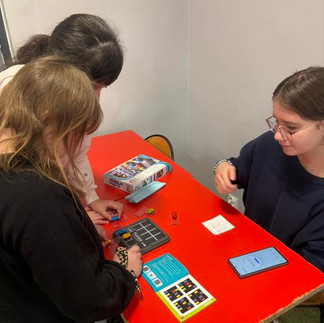 Uczniowie pochyleni nad ławką rozwiązują łamigłówki logiczne.