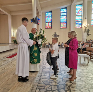 Dwójka dzieci w towarzystwie dyrekcji szkoły ofiaruje dary kapłanowi podczas Mszy Świętej