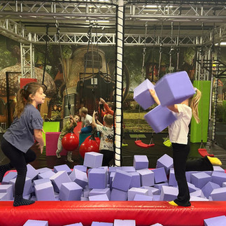 Dzieci rzucają w siebie fioletowymi piankowymi klockami.