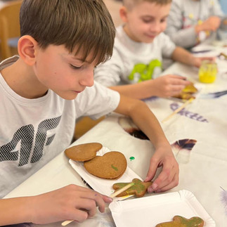 Uczniowie podczas warsztatów dekorują lukrem pierniczki.