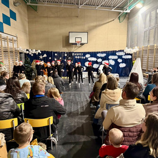 Występ taneczny uczniów przed publicznością zgromadzoną w sali gimnastycznej.