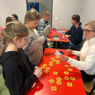 Uczniowie pochyleni nad ławką rozwiązują łamigłówki logiczne.