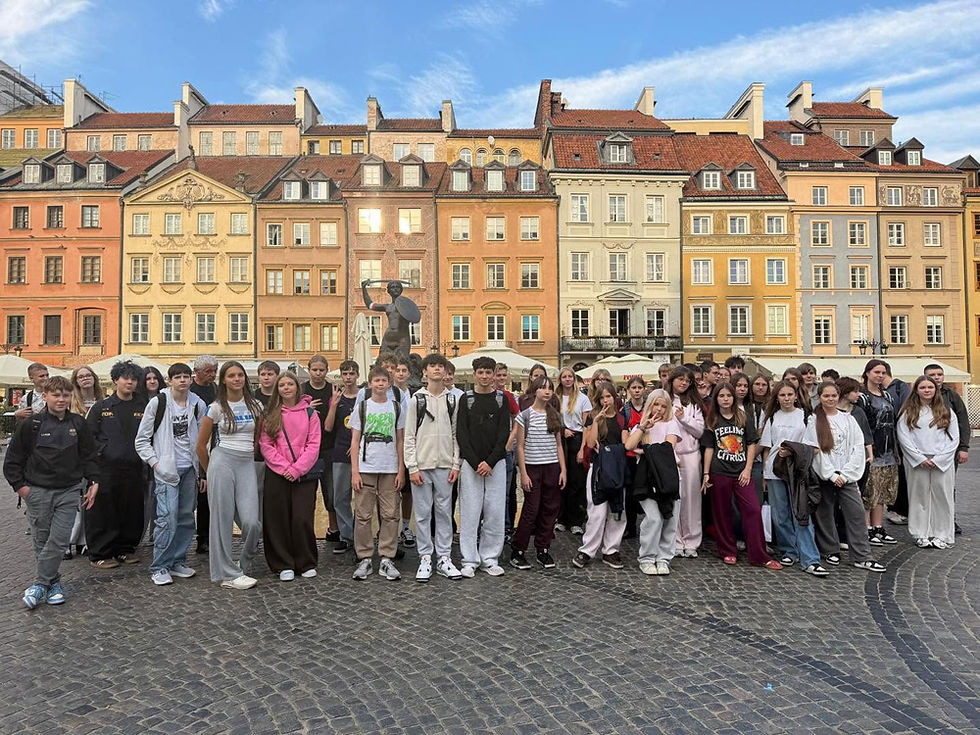 Grupa uczniów na Rynku w Warszawie, w tle kamienice i pomnik Syrenki Warszawskiej
