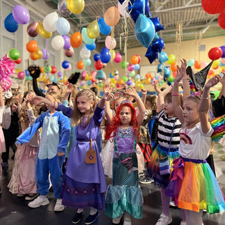 Dzieci w strojach karnawałowych w czasie zabawy w udekorowanej balonami sali.