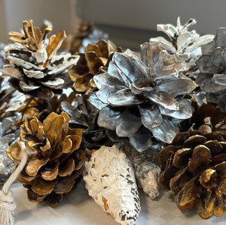 Szyszki sosnowe pomalowane farbkami na kolor złoty, srebrny i biały.