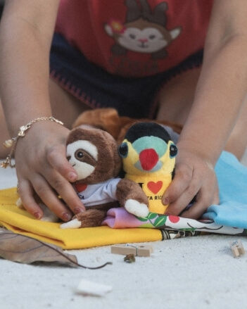 Miniatura: Niña juega con peluches de perezoso y tucán de Costa Rica