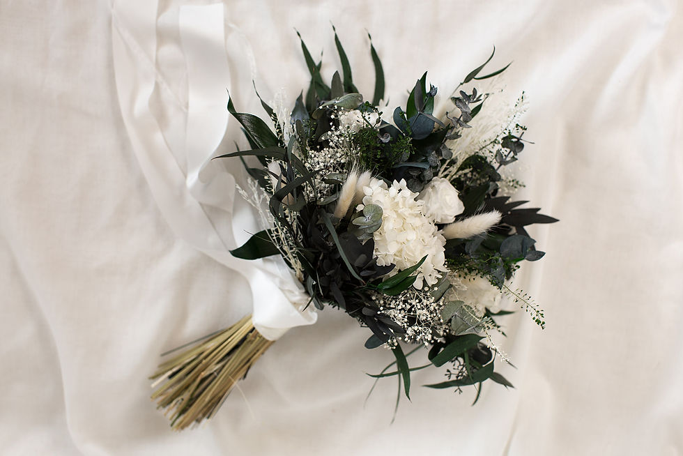 Großer, wilder Brautstrauß aus weißen Infinity-Rosen, Hortensien und dunklem Eukalyptus auf hellem Untergrund.