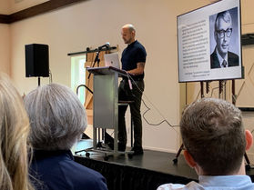 Brett standing at a podium speaking at a conference.