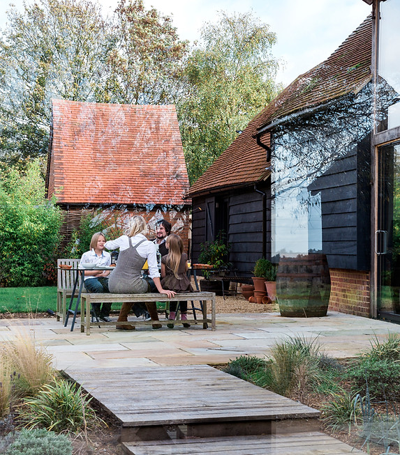 family-sitting-at-bench-outside-countryside-house-2023-11-27-05-02-41-utc.jpg