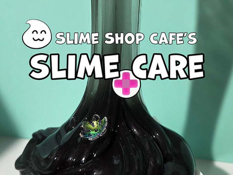Clear obsidian slime being stretched over a pale green background with  iridescent resin flowers on it 