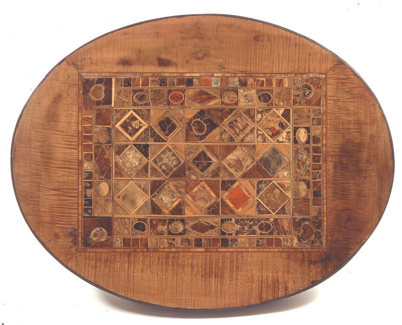 Oval wooden table with colorful geometric inlay mosaic on top, set against a plain white background.