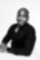 This is a black and white picture of me, Pete the Wizard/Pierre Kasongo dressed in black black shirt, leaning on a white table.