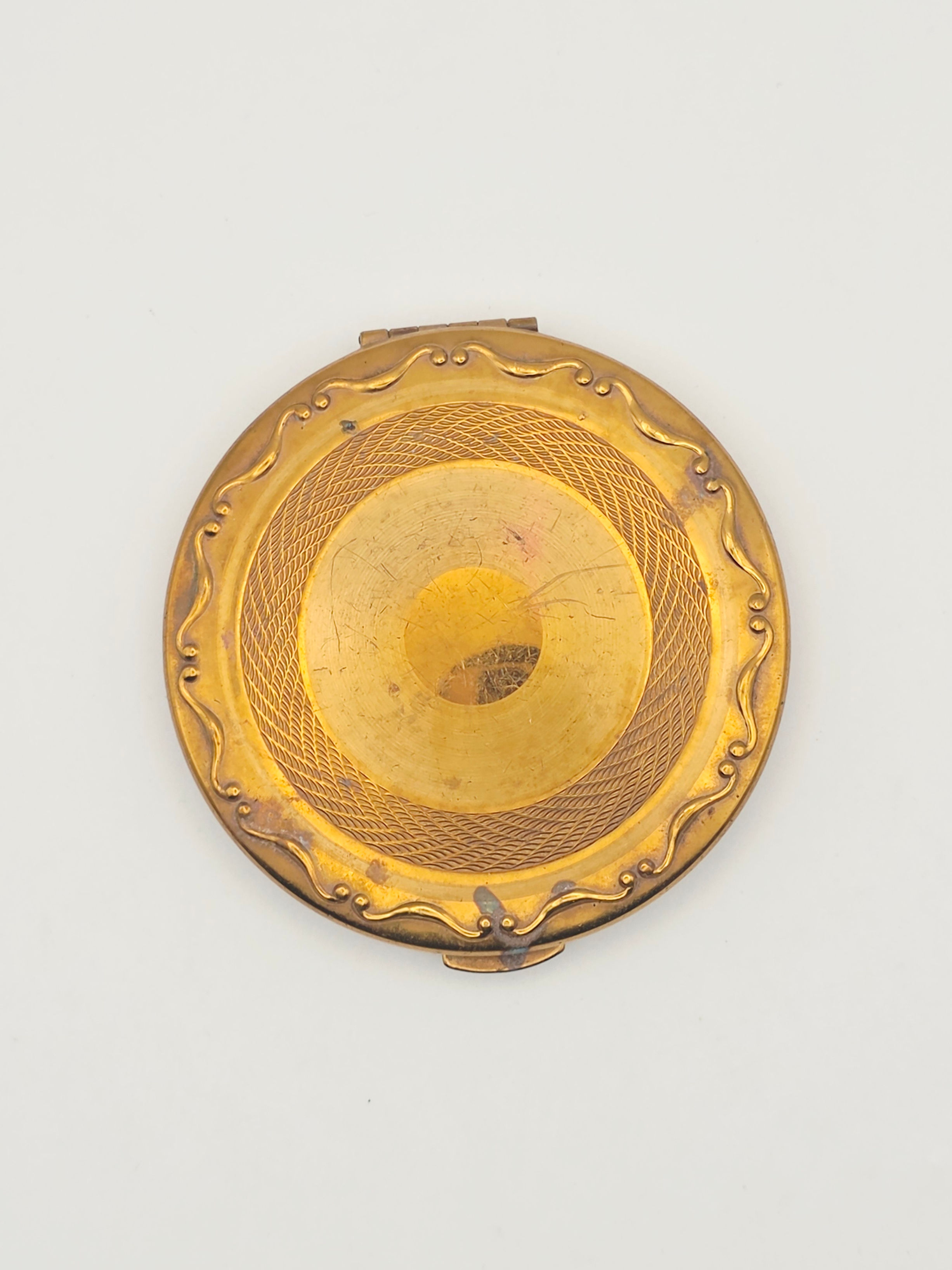 Mid-century Kigu gold tone brass powder compact with scroll border top view