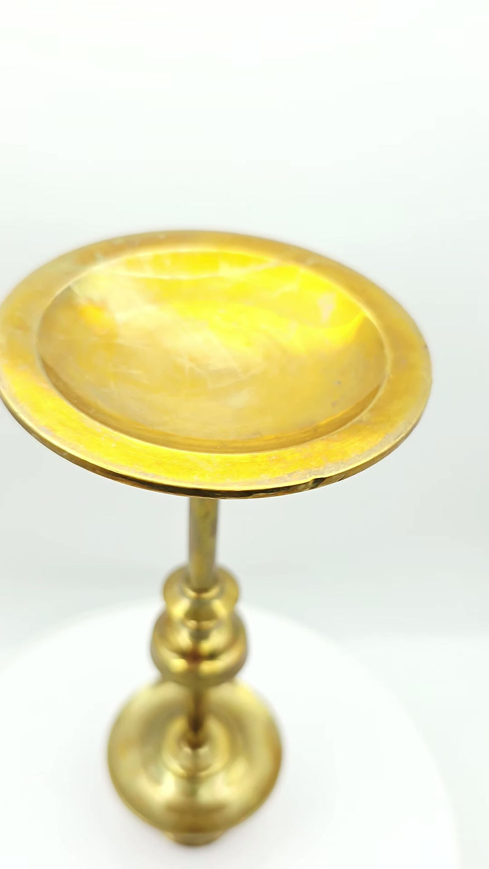 Angle view of stepped brass base showing concentric turned rings and aged patina