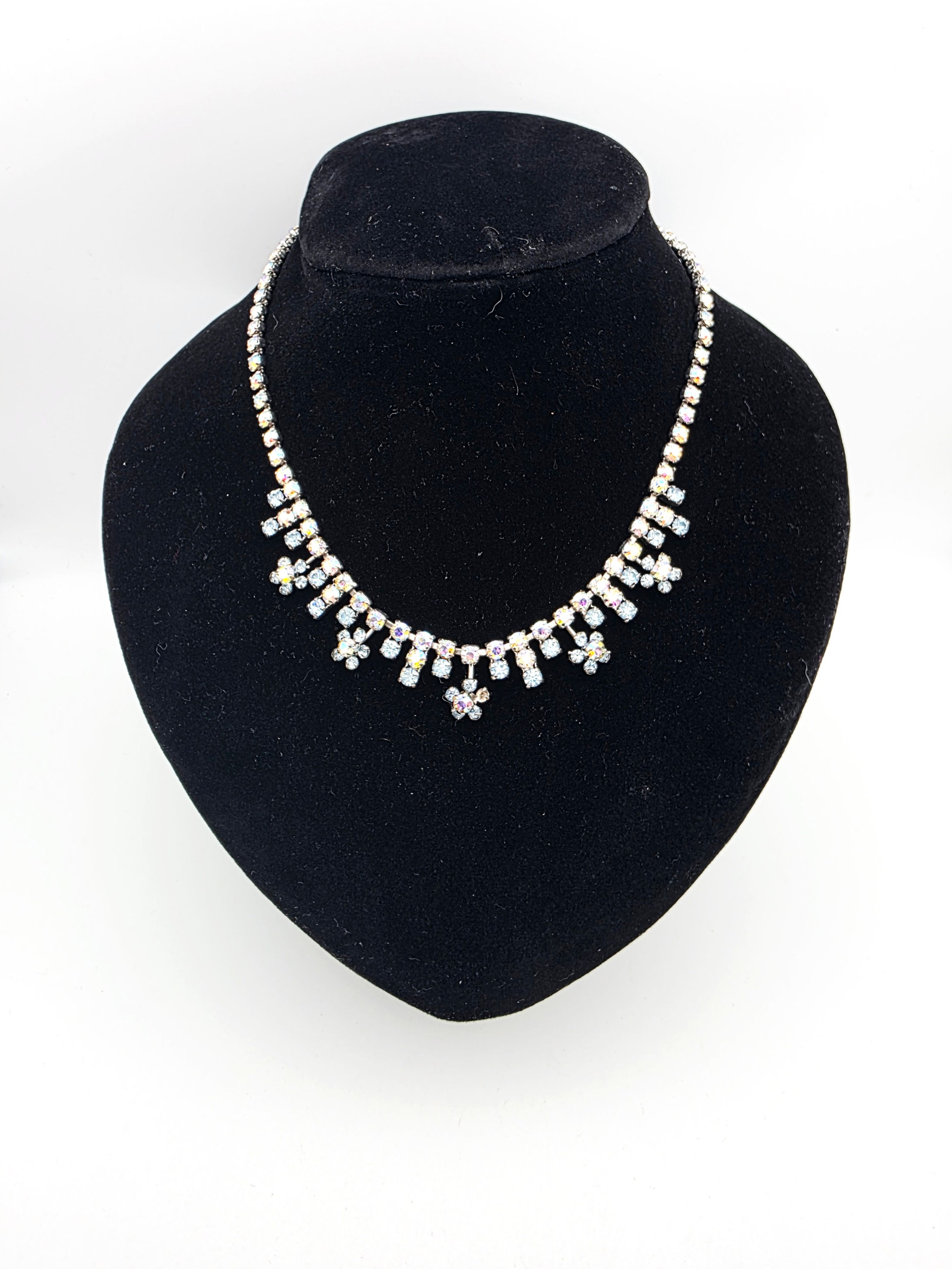 Front view of vintage 1950s Aurora Borealis and ice blue rhinestone fringe necklace on black bust display