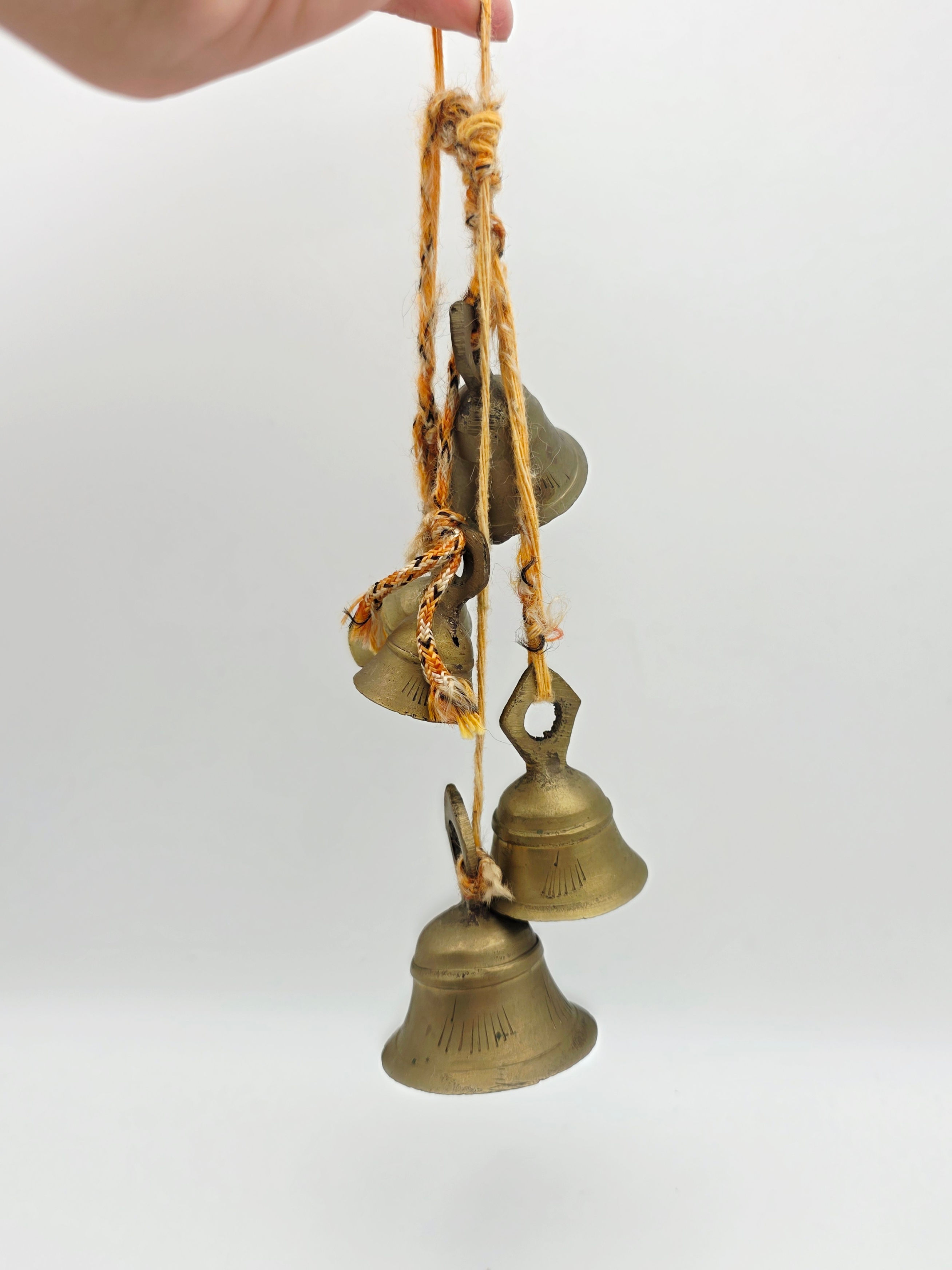 Full length view of five graduated brass hanging bells arranged vertically.
