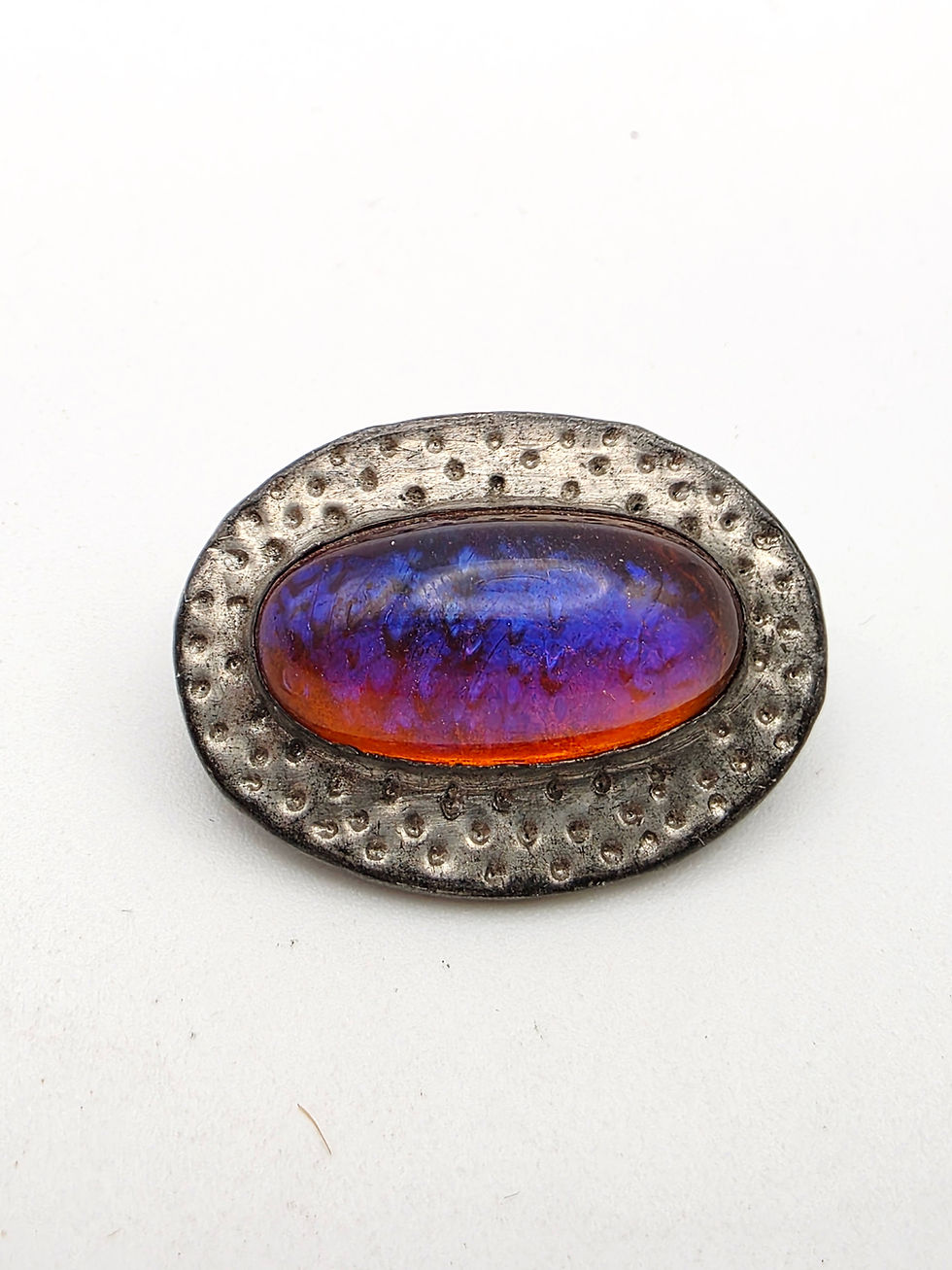 Victorian Arts Crafts dragon fire opal glass brooch flashing blue and purple fire on hammered oval setting.