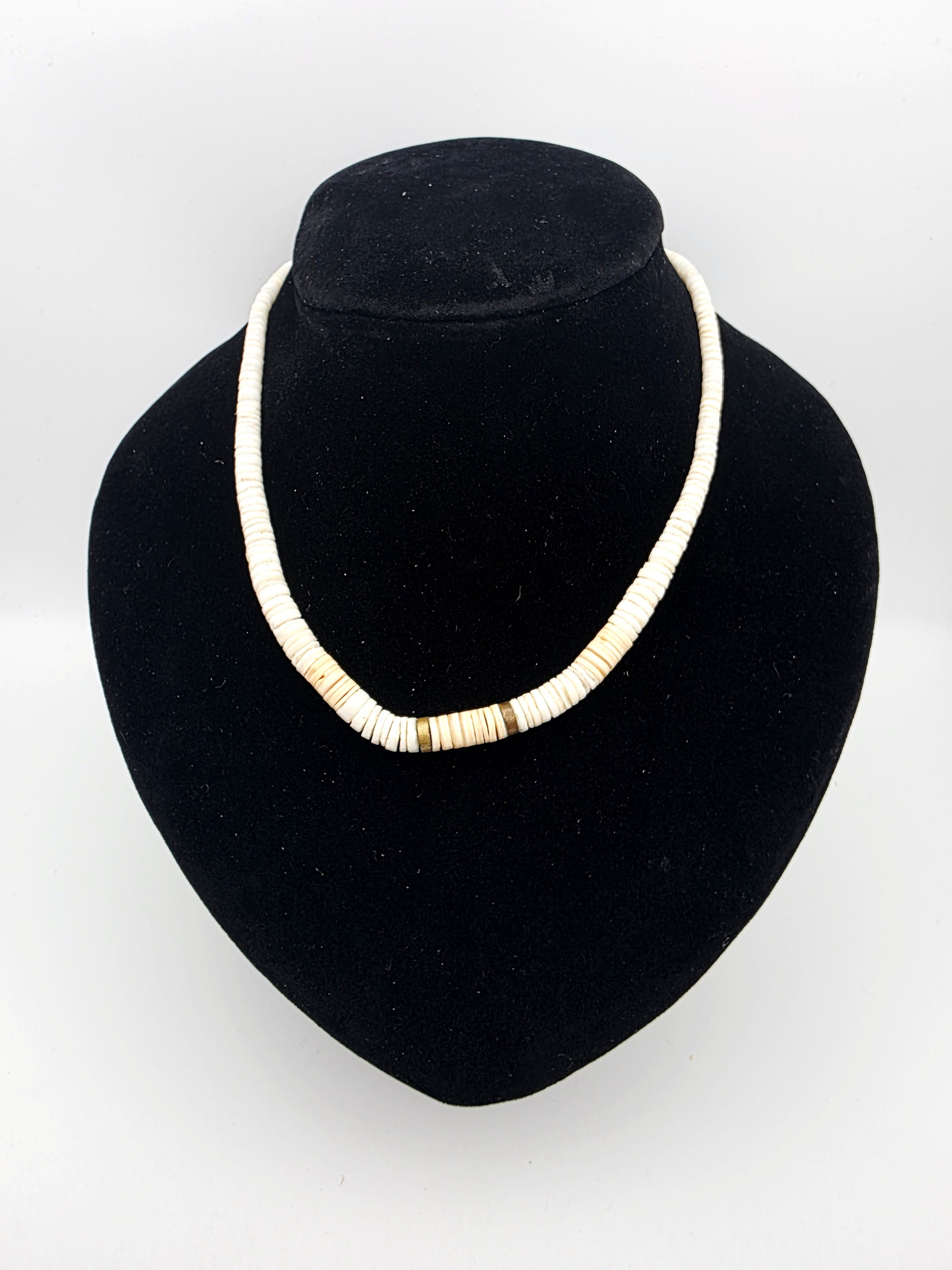 Overview layout of a vintage cream natural shell heishi disc choker necklace displayed on a black velvet bust.