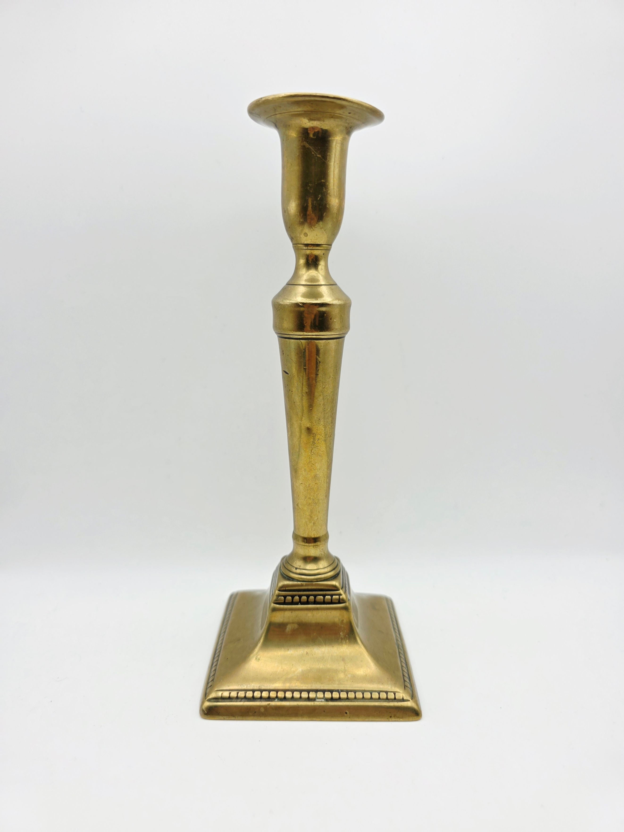 Antique Victorian sand cast brass candlestick with square base on white background