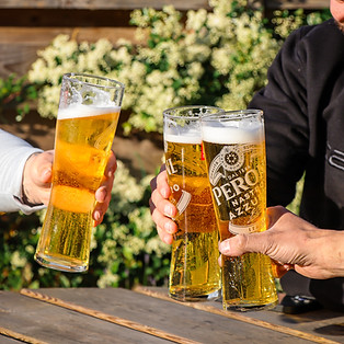 Three glasses of beer being raised in a toast in the garden at The Bird Westhay.