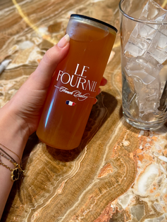 Close-up of Le Fournil’s homemade black iced tea with rose, elegantly served in their branded can on a marble table.