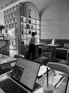 A cozy moment working on a laptop inside Le Fournil, with a view of their chic interior and a rose iced tea nearby.