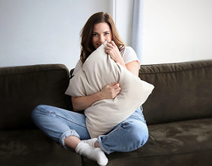 Actress portrait on a sofa with a cushion, bathed in natural light, capturing her relaxed essence by StudioEnBlanco.