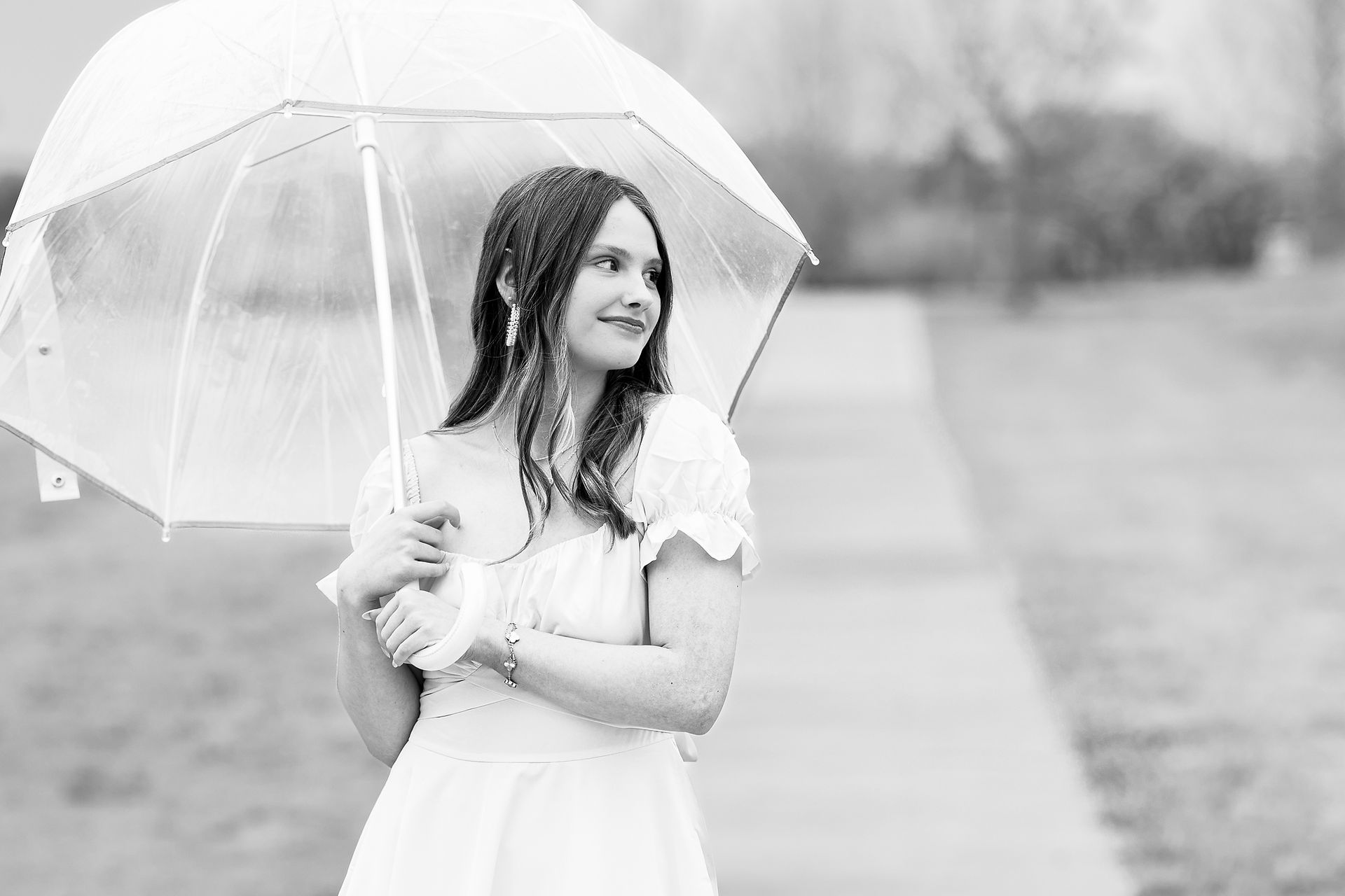 Young woman holding clear umbrella and looking away