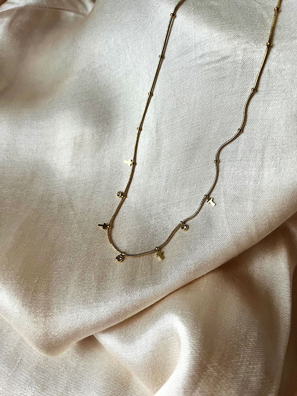 Miniaturbild: Goldene Halskette auf cremefarbenem Seidentuch, zarte Dekoration, nahaufnahme