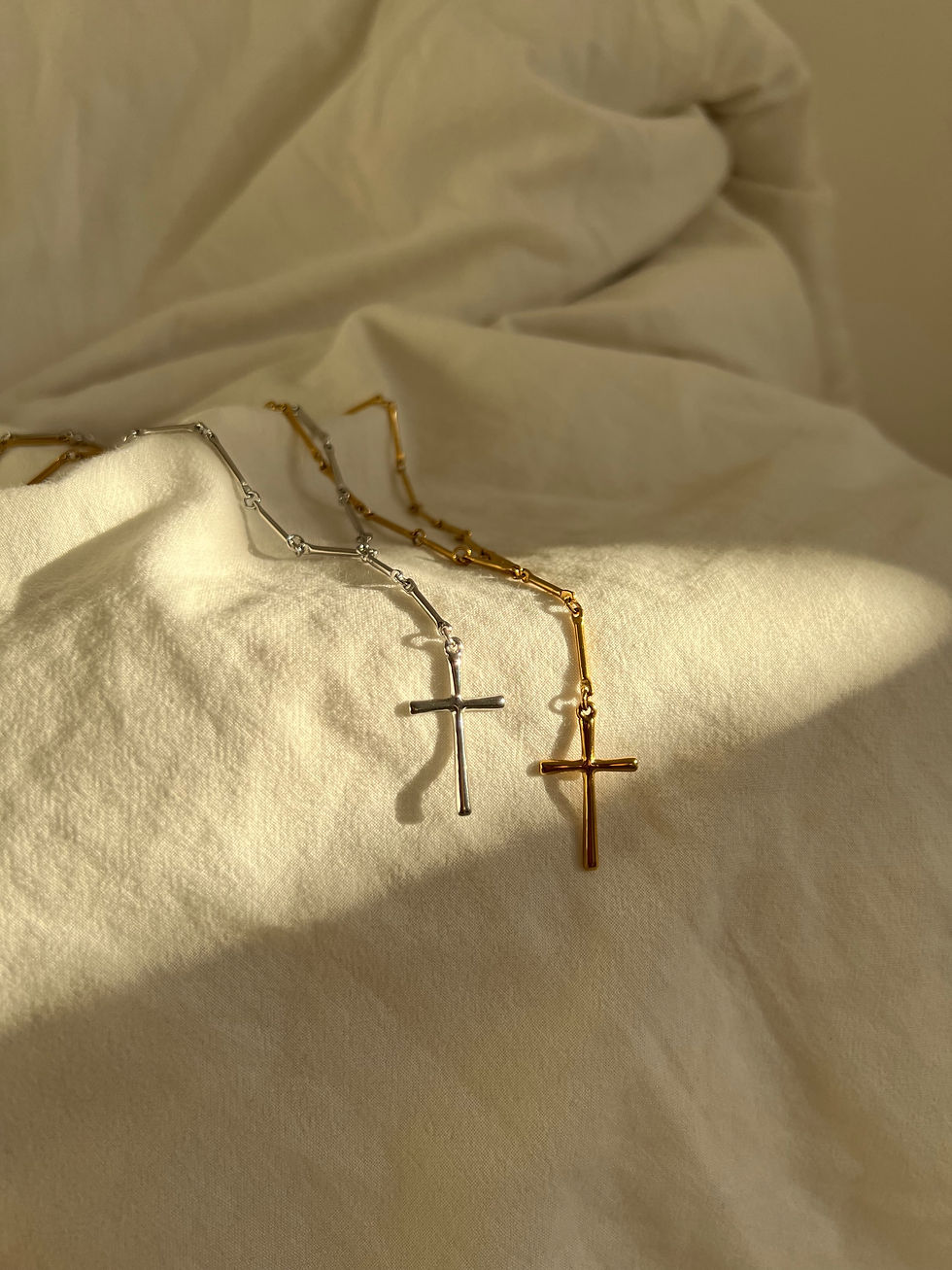 Miniaturbild: Zwei goldene Kreuze auf weißem Stoff, Schmuck, minimalistisches Design, modisch.