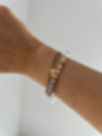 Handgelenk mit goldene Armbänder, Kreuzanhänger und Perlen. Schmuck Accessoire, schlichte Hintergrund.