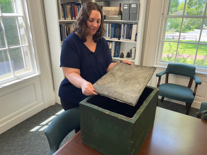 Sandwich Town Archivist Jen Ratliff holds the tin lid that protected the contents of the Centennial Box, one of America's oldest time capsules.