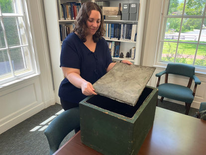 Sandwich Town Archivist Jen Ratliff holds the tin lid that protected the contents of the Centennial Box, one of America's oldest time capsules.