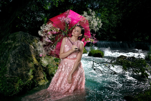 Woman with red umbrella and flowers standing in a river