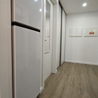 Geladeira branca em corredor com piso de madeira no Apartamento 1
