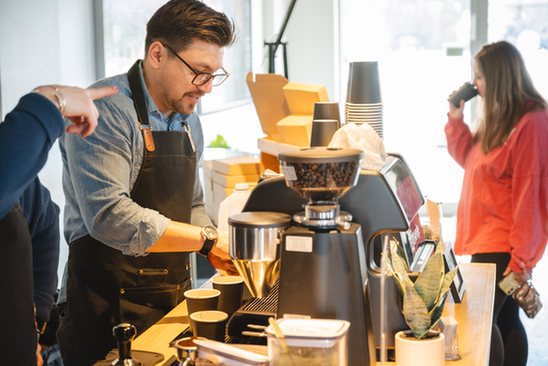 Barista wearing glasses and apron preparing coffee drinks