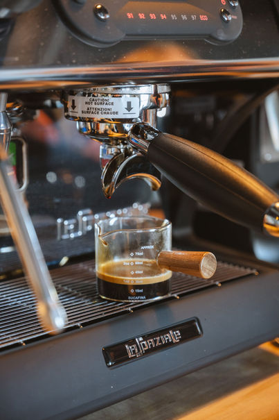 Espresso pouring into a glass pitcher from a machine
