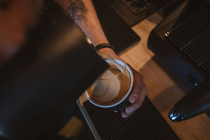 Barista pouring steamed milk into coffee for latte art