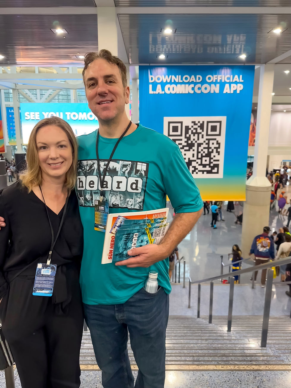 Alex and his wife Lindsay posing with leaflets and flyers in the lobby at LA Comic Con.