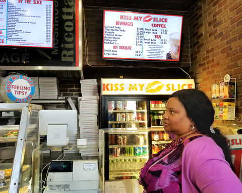 A salesperson awaits customers queued up at a popular Manhattan pizza joint.