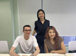Group photo of diverse people smiling in a bright classroom setting.