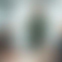 A ginger haired man leading a meeting with colleagues gathered around a wooden table in a modern glass office.