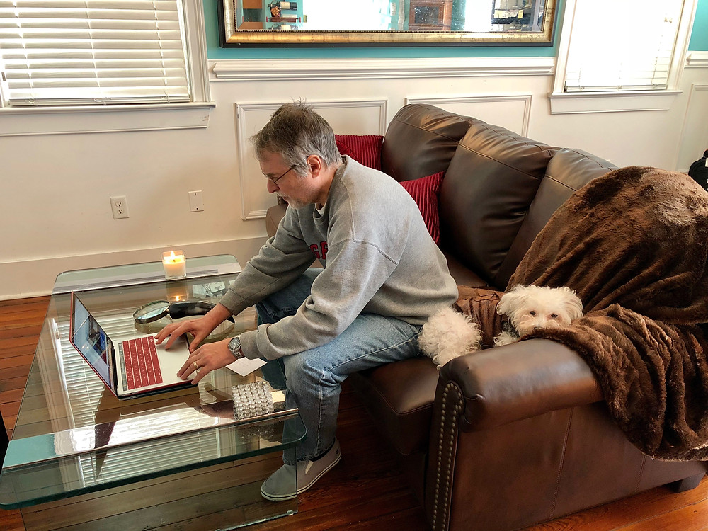 Man working at home on laptop with dog