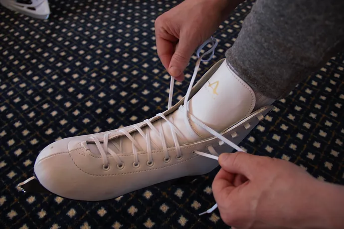 Tying white figure skates