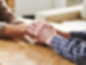 Two persons' hands are joined in a sign of compassion